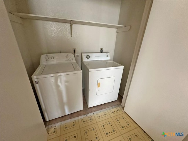 laundry area featuring light floors, separate washer and dryer, and laundry area