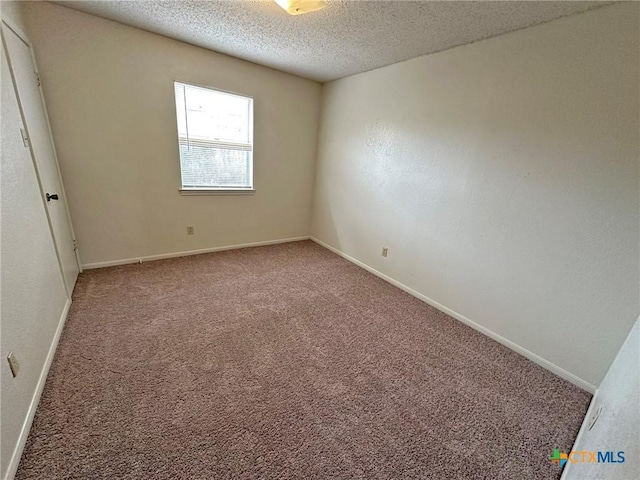 carpeted empty room with a textured ceiling and baseboards