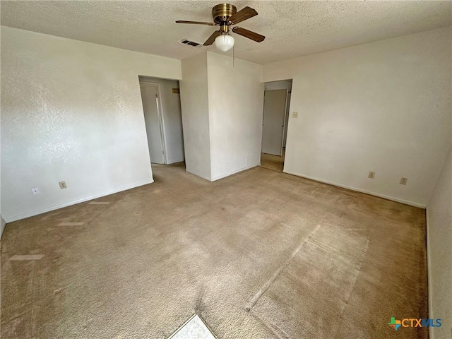 empty room with ceiling fan, visible vents, a textured ceiling, and carpet flooring