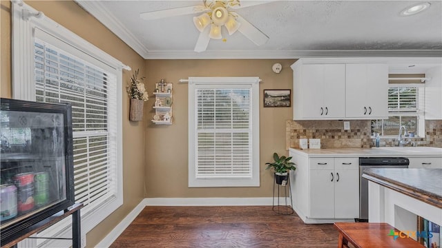 kitchen with dark wood-type flooring, sink, white cabinetry, stainless steel dishwasher, and ornamental molding