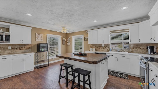 kitchen with sink, stainless steel appliances, dark hardwood / wood-style floors, a center island, and white cabinets