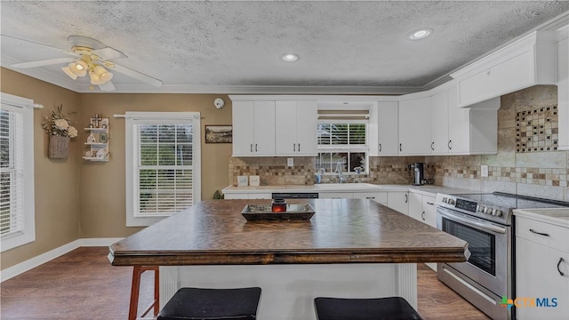 kitchen with sink, white cabinetry, backsplash, hardwood / wood-style floors, and stainless steel appliances