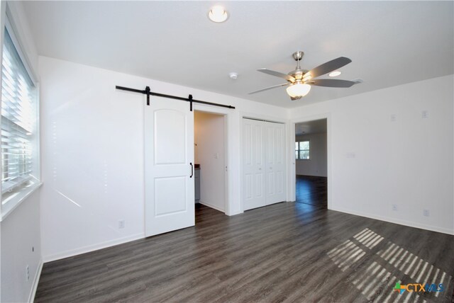 spare room with dark hardwood / wood-style floors, a barn door, and ceiling fan