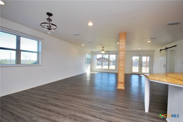 interior space featuring ceiling fan with notable chandelier, french doors, a barn door, and dark hardwood / wood-style floors