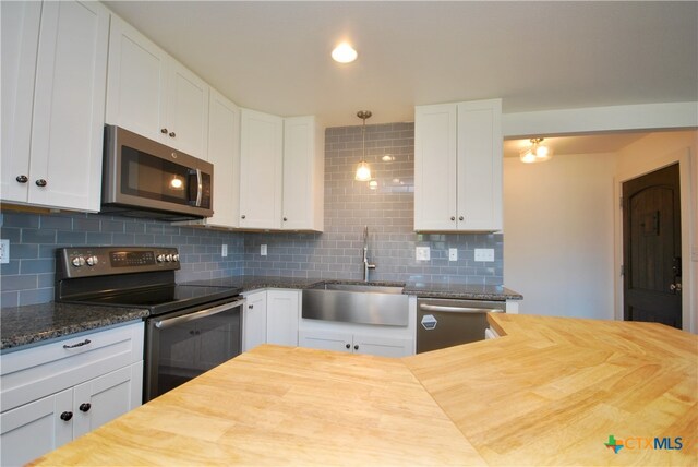 kitchen with white cabinetry, sink, wood counters, decorative backsplash, and appliances with stainless steel finishes