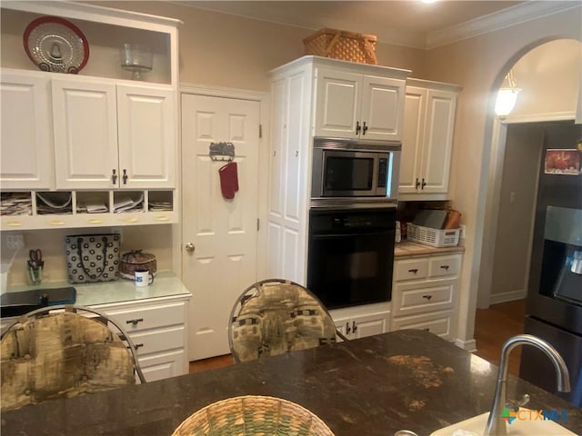 104 Woodcreek Cir, Victoria, TX 77904 - kitchen with oven, stainless steel microwave, fridge with ice dispenser, white cabinetry, and crown molding