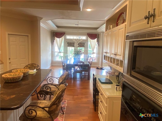 104 Woodcreek Cir, Victoria, TX 77904 - kitchen with oven, a raised ceiling, stainless steel microwave, wood finished floors, and a chandelier