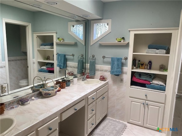 104 Woodcreek Cir, Victoria, TX 77904 - full bathroom with tile walls, double vanity, toilet, wainscoting, and tile patterned flooring