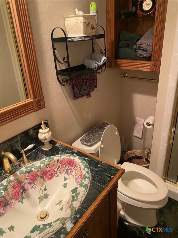 104 Woodcreek Cir, Victoria, TX 77904 - bathroom featuring vanity, toilet, and a shower with door