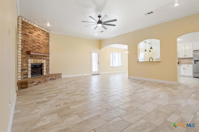 1129 Wren Cir, Copperas Cove, TX 76522 - unfurnished living room featuring a ceiling fan, arched walkways, a brick fireplace, ornamental molding, and recessed lighting