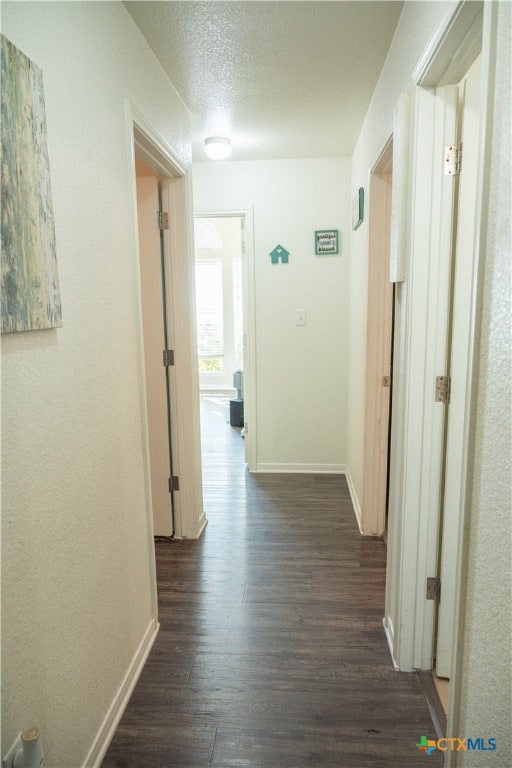 corridor with dark wood-type flooring and a textured ceiling