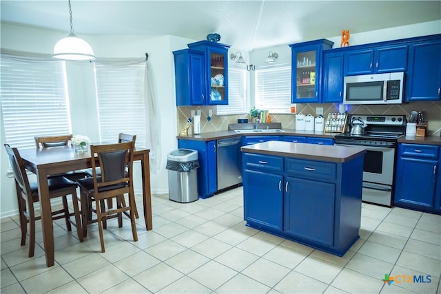 kitchen featuring decorative backsplash, blue cabinetry, decorative light fixtures, a kitchen island, and stainless steel appliances