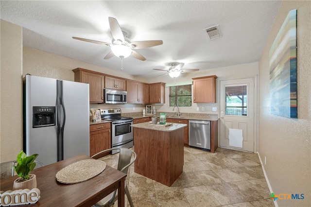 kitchen featuring a kitchen island, appliances with stainless steel finishes, sink, and a textured ceiling