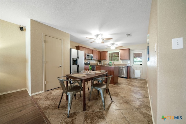 dining space with ceiling fan, sink, and a textured ceiling