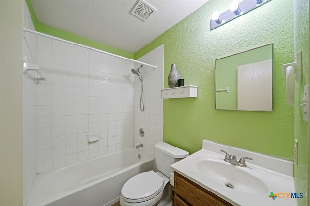 full bathroom with vanity, tiled shower / bath, a textured ceiling, and toilet