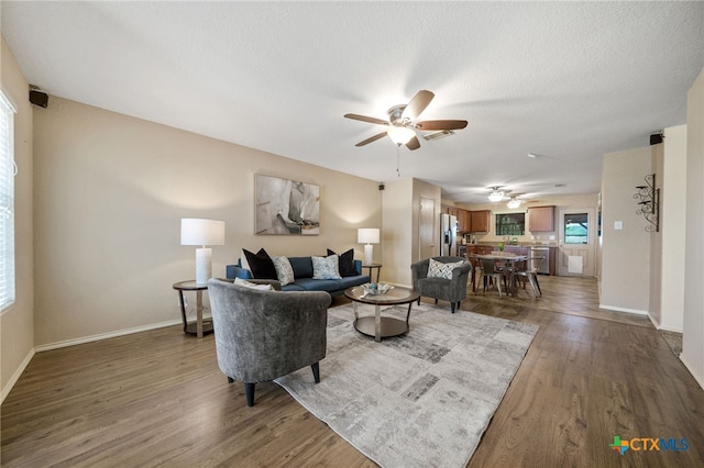 living room featuring ceiling fan, dark hardwood / wood-style floors, and a textured ceiling