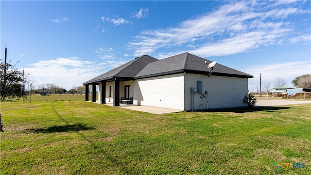 view of side of home featuring a patio area and a lawn