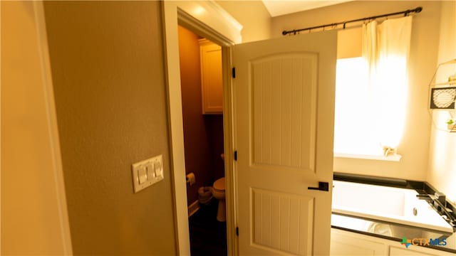 bathroom with a tub to relax in and toilet