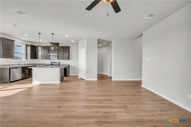 kitchen with decorative light fixtures, a kitchen island, light wood-type flooring, and stainless steel appliances