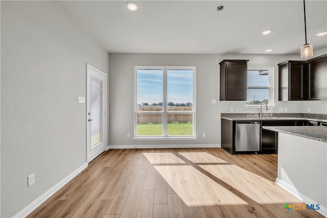 kitchen featuring light wood-type flooring, stainless steel dishwasher, dark brown cabinets, pendant lighting, and stone counters