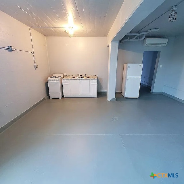 finished basement with a sink, baseboards, freestanding refrigerator, and a wall mounted air conditioner