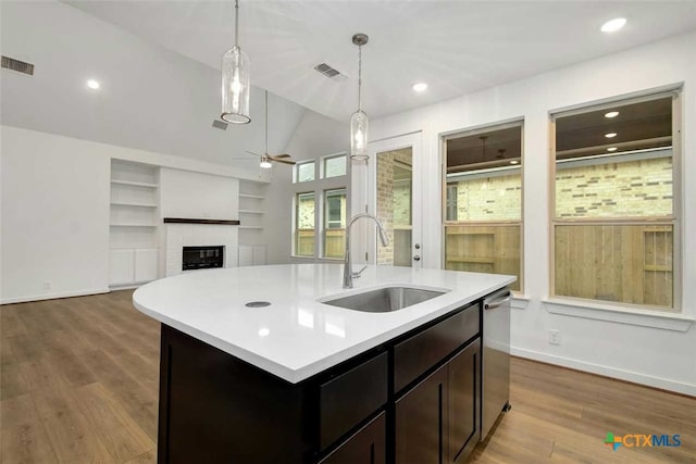 kitchen featuring an island with sink, sink, light wood-type flooring, and lofted ceiling