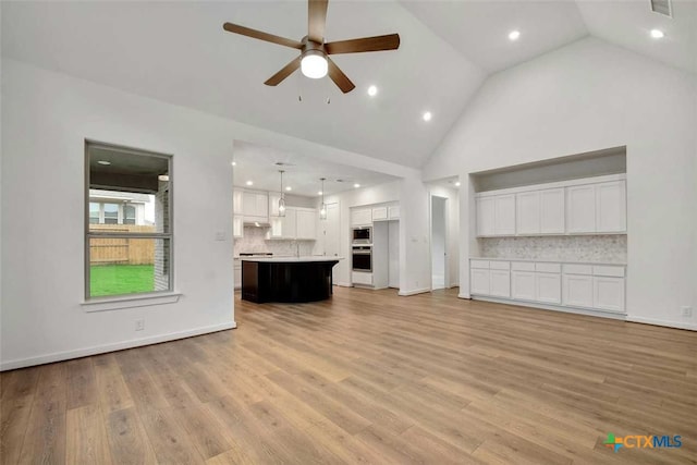 unfurnished living room with light wood-type flooring, ceiling fan, and high vaulted ceiling