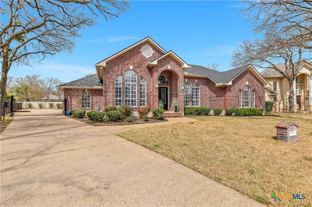 view of front of home with driveway, brick siding, a front lawn, and a gate