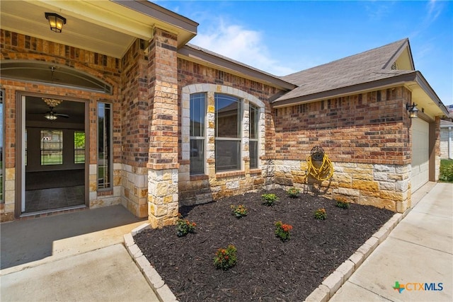 property entrance featuring an attached garage, brick siding, and stone siding