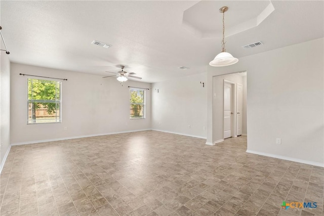 spare room featuring ceiling fan, a healthy amount of sunlight, and visible vents