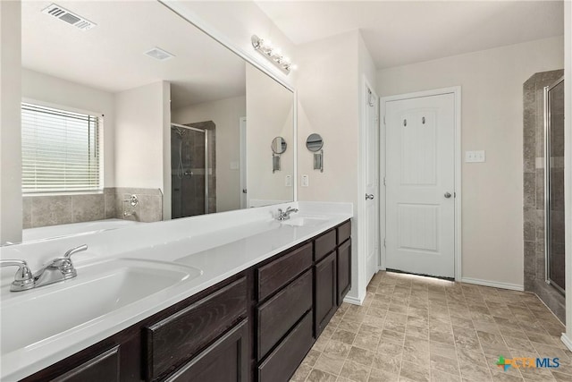full bathroom featuring visible vents, a sink, a shower stall, and double vanity