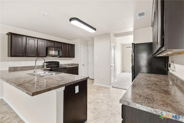 kitchen featuring visible vents, a sink, dark brown cabinetry, black appliances, and a peninsula