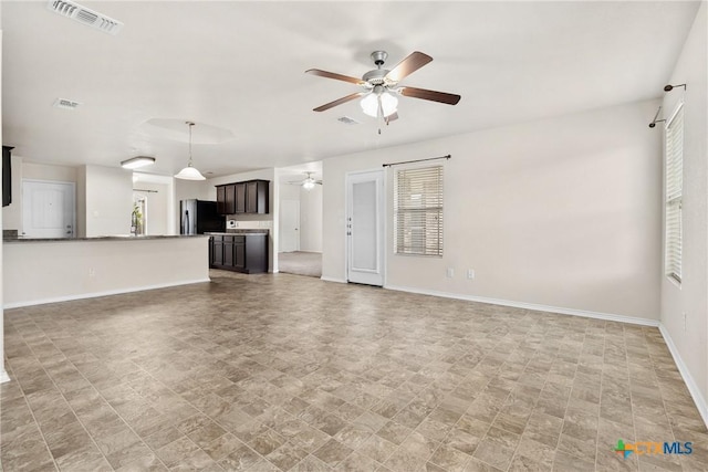 unfurnished living room with visible vents, a ceiling fan, and baseboards