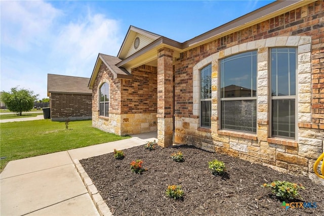exterior space featuring brick siding, stone siding, and a front yard