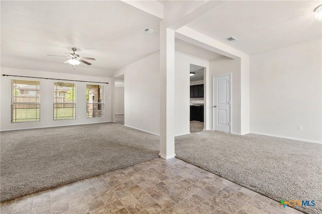 unfurnished living room with a ceiling fan, light carpet, stone finish flooring, baseboards, and visible vents