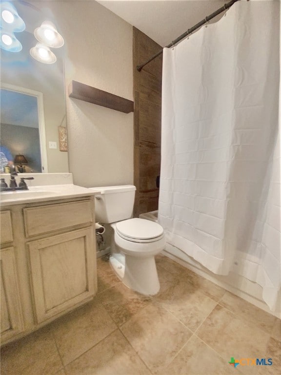 bathroom featuring toilet, shower / bath combo with shower curtain, and vanity