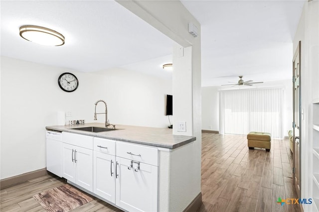 kitchen featuring sink, light hardwood / wood-style flooring, white dishwasher, white cabinets, and kitchen peninsula