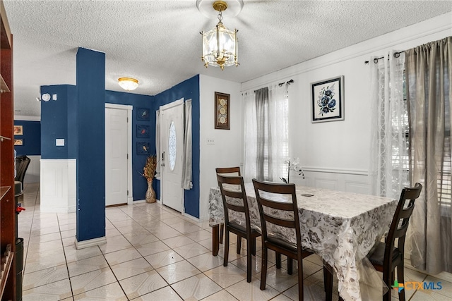 tiled dining area featuring a textured ceiling and a notable chandelier