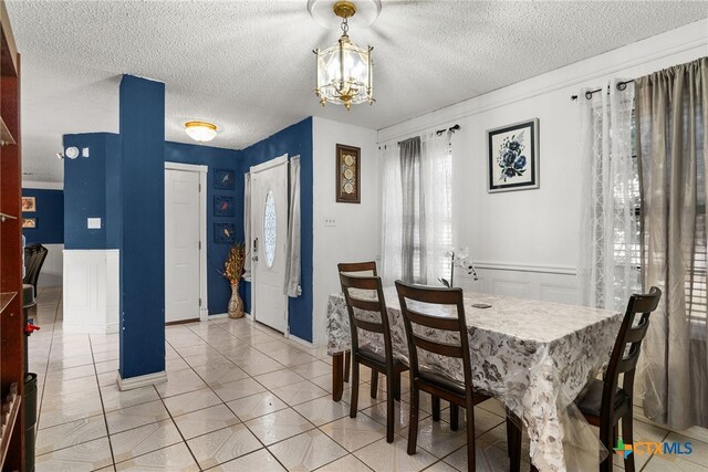 517 Margaret Lee St, Copperas Cove, TX 76522 - dining room featuring a textured ceiling, a chandelier, a wainscoted wall, and light tile patterned floors