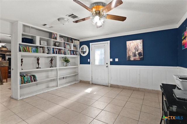 tiled entryway featuring ceiling fan and crown molding