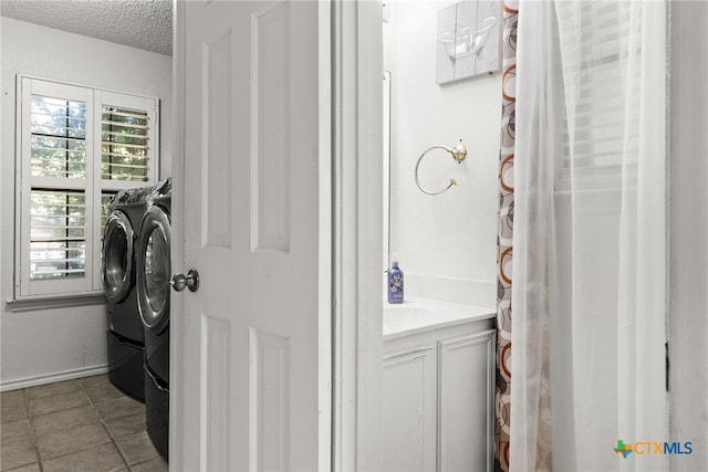 washroom with tile patterned floors, a textured ceiling, and washer and dryer