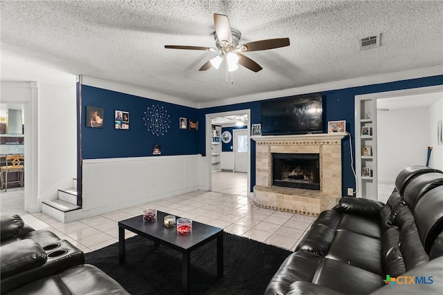 517 Margaret Lee St, Copperas Cove, TX 76522 - tiled living area with ceiling fan, a tiled fireplace, wainscoting, and a textured ceiling