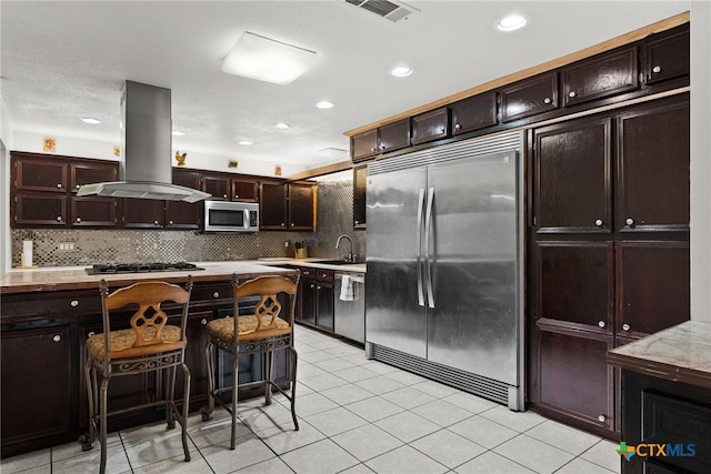 kitchen with tasteful backsplash, island exhaust hood, light tile patterned flooring, and stainless steel appliances