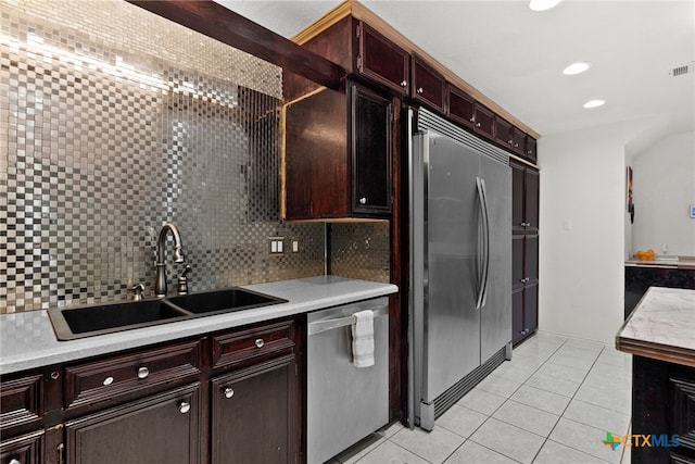 kitchen with stainless steel appliances, light tile patterned floors, sink, and backsplash