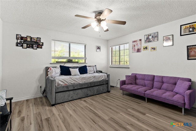 living room featuring light hardwood / wood-style floors, ceiling fan, and a textured ceiling