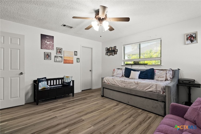 bedroom with ceiling fan, wood-type flooring, and a textured ceiling