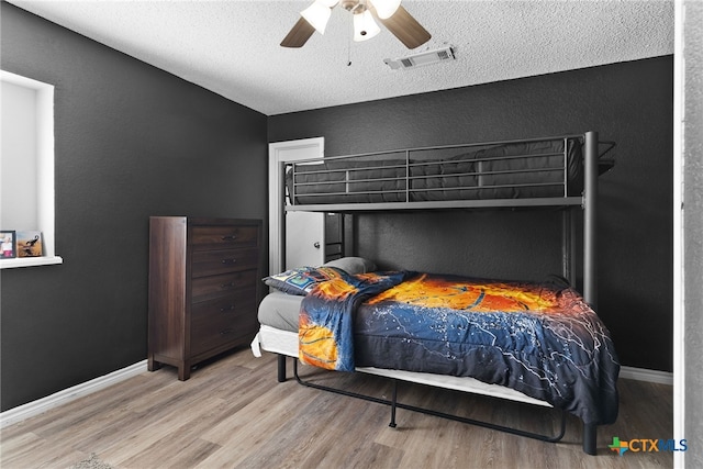 bedroom with light wood-type flooring, a textured ceiling, and ceiling fan