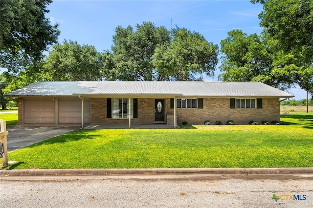 ranch-style home featuring covered porch, a garage, and a front yard