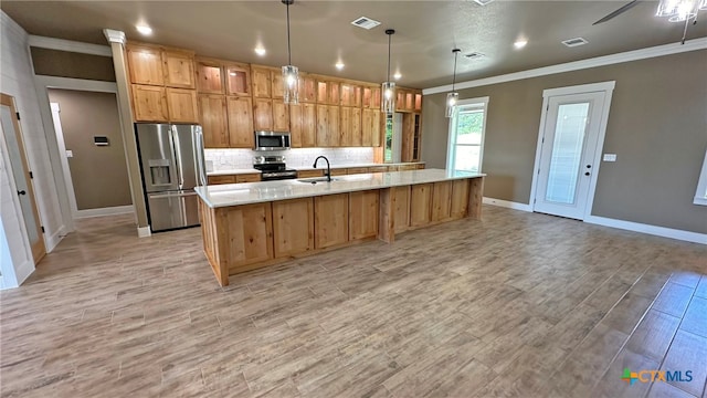 kitchen with sink, appliances with stainless steel finishes, decorative light fixtures, and light hardwood / wood-style floors