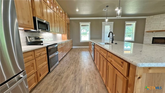 kitchen featuring stainless steel appliances, a large island, pendant lighting, sink, and light hardwood / wood-style flooring